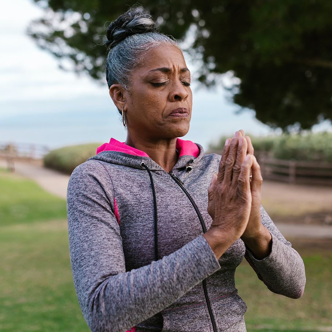 Una adulta mayor meditando en el parque.